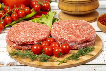 Raw hamburger patties on wood background. Raw veal hamburger patties with herbs and spices. Close up