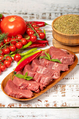 Raw beef tenderloin on wood background. Raw beef tenderloin with herbs and spices