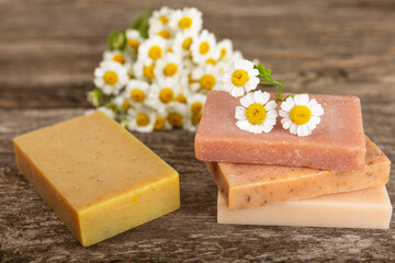 Natural homemade soap with chamomile flowers on a wooden table. Close-up of moisturizing soap with natural herbal oils. Spa and beauty concept. Place for text. Copy space.Fletley