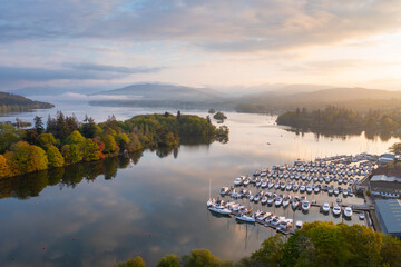 Beautiful sunrise over still lake and boats in a marina. Windermere, Lake District UK