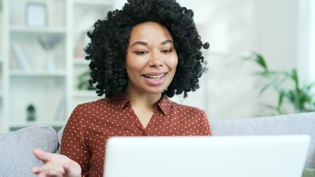 Close Up. Young African American Businesswoman Talking On A Video Call Using A Laptop Sitting On Couch In Home Office. Black Woman Freelancer Communicates At An Online Meeting, Consultation Or Webinar