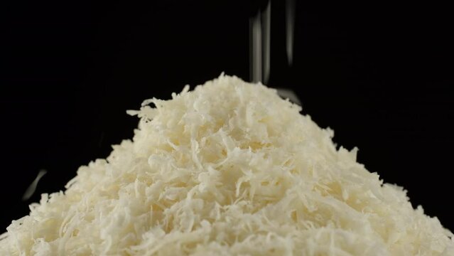 Grated cheese parmesan falling down, black background