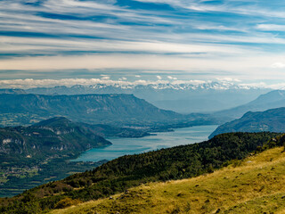 View of Lake Bourget seen from Grand Colombier summit, sky streaked with clouds, Alps in the...
