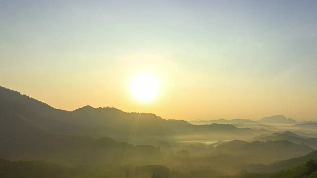 aerial hyper lapse view golden sunrise in Phang Nga valley on the mountain range..the sun shone through the fog in the valley..The yellow light from the sky illuminated the misty valley.