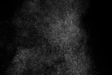 Abstract splashes of water on black background. Freeze motion of white particles. Rain, snow...