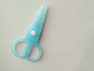 Close up of a blue plastic scissors isolated on white background. Safe small scissor for children