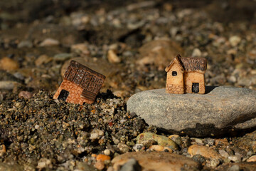 Two miniature houses in sand and on rock (stone). Close-up. Wise and solid foundation gospel parable of Jesus Christ, obedience, and faith in God. Christian biblical concept. - obrazy, fototapety, plakaty