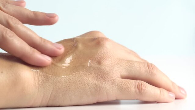 Female hands care. Close up shot of woman applying cream on hand skin. Serum oil with hyaluronic acid applied by a woman's hand, skin care cosmetics, moisturizing gel.