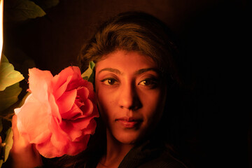 a beautiful brown south asian indian woman laying down with a flower in her front - obrazy, fototapety, plakaty
