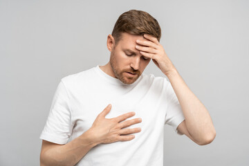 Middle aged man feeling bad puts hand to chest, keeping head having heart pain, headache. Male...