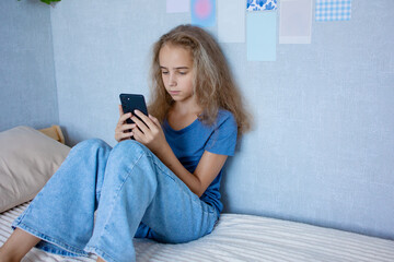 A cute teenage girl communicates via video over the Internet using a smartphone with her friends and classmates. Writes a message or speaks on speakerphone.