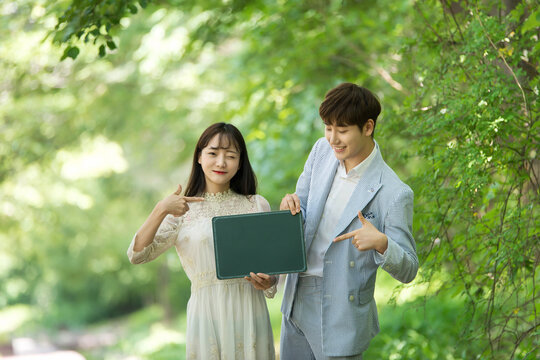 A loving couple are taking wedding photos with green boards outdoors for their wedding.