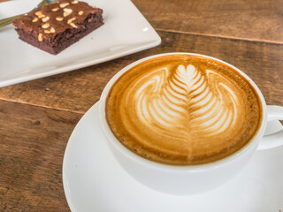 latte art rosetta in a white cup with brownie