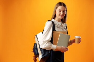 Teen girl in school uniform carry backpack on yellow background