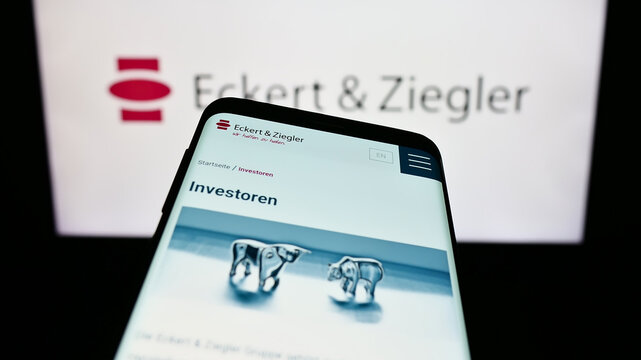 Stuttgart, Germany - 09-09-2023: Mobile phone with webpage of Eckert Ziegler Strahlen- und Medizintechnik AG on screen in front of logo. Focus on top-left of phone display.