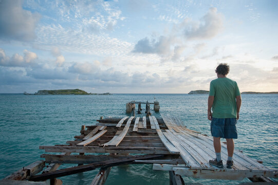 A Young Man Stands On A Wooden Dock In Disrepair; South Caicos Turks And Caicos Islands