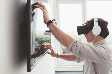young adult man playing videogame with 3D viewer interacting with smart screen