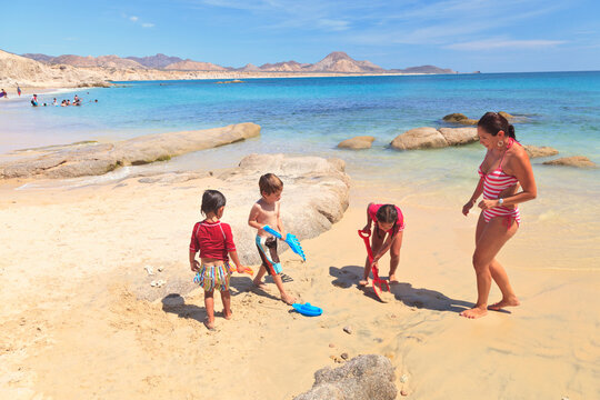 A Mother Plays With Her Three Children On A Beach; San Jose Del Cabo, Baja California Sur, Mexico