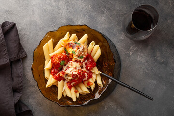 Penne pasta with meatballs in tomato sauce on the plate and a glass of wine top view