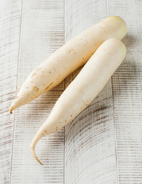Daikon on a white wooden background. Healthy food, vegetables.