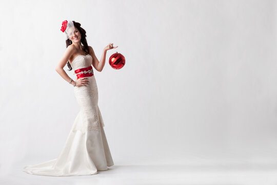 Portrait Of A Young Woman Wearing A White Strapless Formal Dress With Red Accessories Against A White Background; Nashville, Tennessee, United States of America