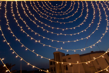 Small White Lights Strung In A Circular Pattern Against A Night Sky; Ludhiana, Punjab, India