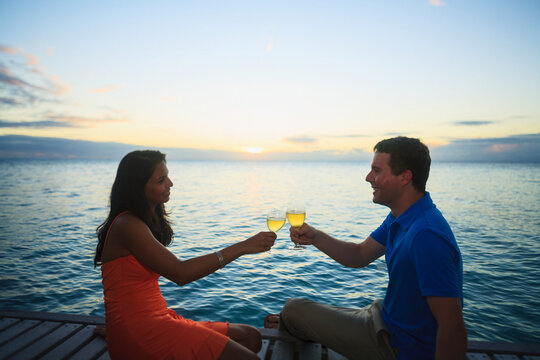 A man and woman give a toast with drinks at the bora bora nui resort and spa; Bora bora island society islands french polynesia south pacific