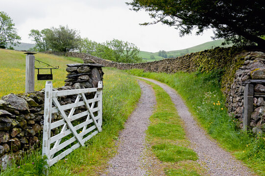 Gravel road leading through a gate along a stone wall; Kentmere cumbria england