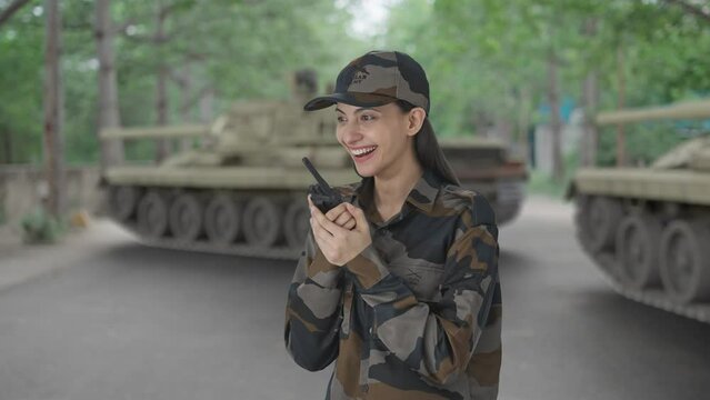 Happy Indian woman army officer talking on walkie talkie