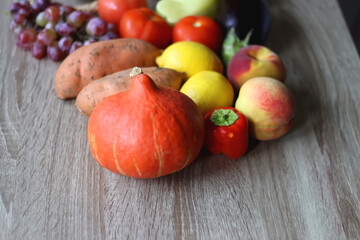 Round straw bag with seasonal fruit and vegetable on wooden background. Late summer or early autumn. Selective focus.