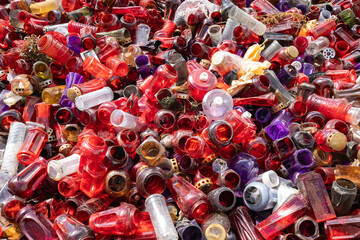 Heap of colorful plastic waste, white, purple, and red grave candle lanterns sorted for recycling,...