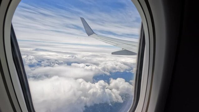 Aircraft plane Wing of flying in clouds and blue sky airplane as seen by passenger through porthole windows. wide view 