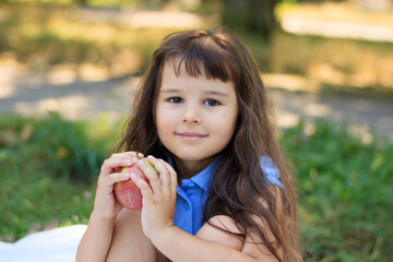Cute little preschooler girl eating an apple on beautiful