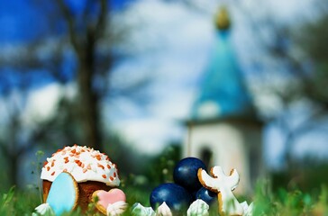 Easter cake, blue eggs dyed with carcade and biscuits in the form of an angel and egg on the grass with bokeh background.
