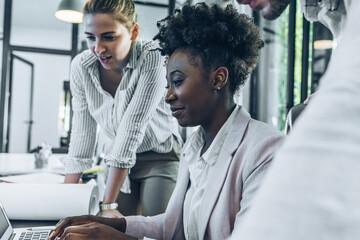 Pretty black female manager discussing ideas at the office of a new startup project. She sits with...