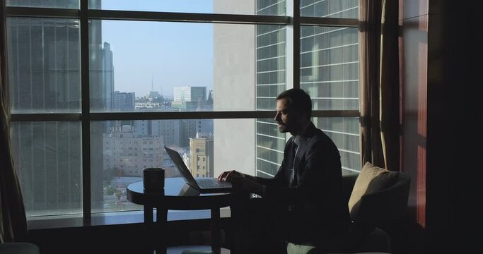 Silhouette of businessman making video call conferencing talking via video call near the windows overlooking the city