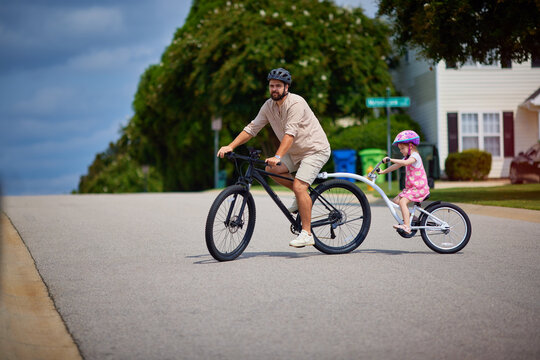 father and daughter, young kid cycling together. bicycle with towable bike trailer. active lifestyle for family with kids