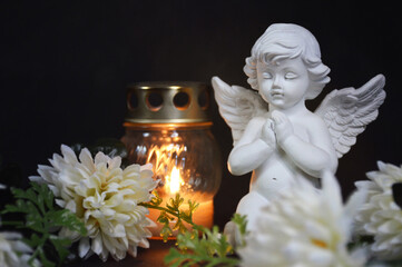 Angel, votive candle and flowers on black background - obrazy, fototapety, plakaty