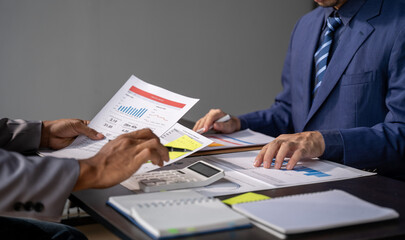 Young colleagues discuss business and analytical price charts using calculators and laptops to calculate financial, tax, accounting, statistics and analytical research ideas.