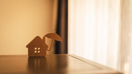 Model of umbrella with house on wooden table concept of the system of insurance savings and Housing...