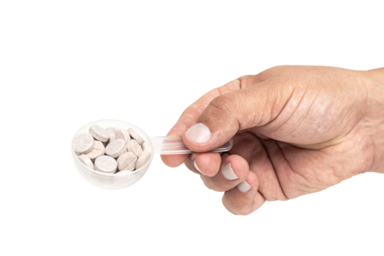 Male hand holds plastic measuring spoon with round therapeutic pills or drugs for treatment isolated transparent white background, medicine and healthcare concept, close-up view