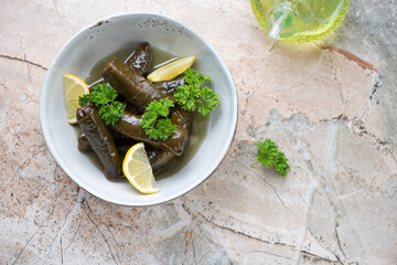 Grey bowl with greek dolma or dolmades on a pinkish granite background, horizontal shot with space, above view