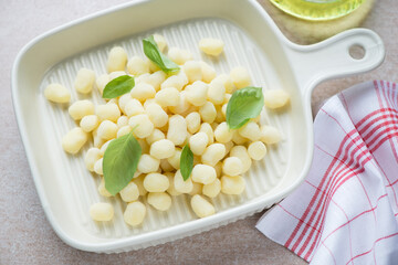 Light-beige serving tray with italian gnocchi or chicche di patate, horizontal shot, selective focus