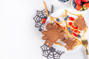 Funny kids breakfast for Halloween. Creative homemade sweet pancakes in form of traditional Halloween monsters and symbols, with fresh berry, chocolate and red syrup