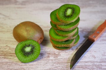 Closeup on ripe green kiwi fruits cut in slices on a wooden background. Healthy eating concept.