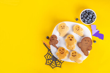 Funny kids breakfast for Halloween. Creative homemade sweet pancakes in form of traditional Halloween monsters and symbols, with fresh berry, chocolate and red syrup
