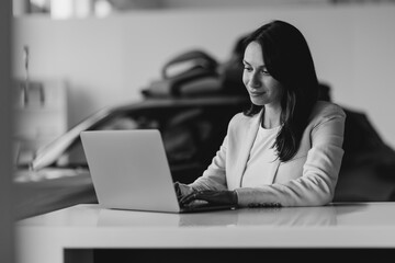 Business woman working on a laptop at the office of car showroom