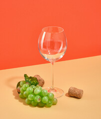 A wine or champagne glass, a ripe bunch of green sweet grapes on the table.