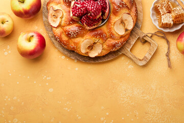 Jewish Holidays - Rosh Hashanah or Rosh Hashana. Pomegranate, apples, honey and round challah on rustic yellow table background. Jewish Autumn celebration. Shana Tova. Yom kippur concept. Top view.