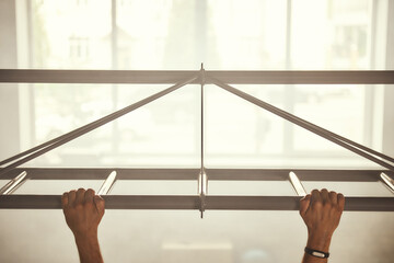 Cropped photo of a man doing pull-ups while exercising in the gym.